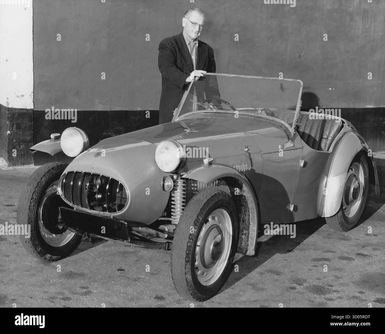 Mann, der neben einem Oldtimer-Sportwagen steht Stockfoto