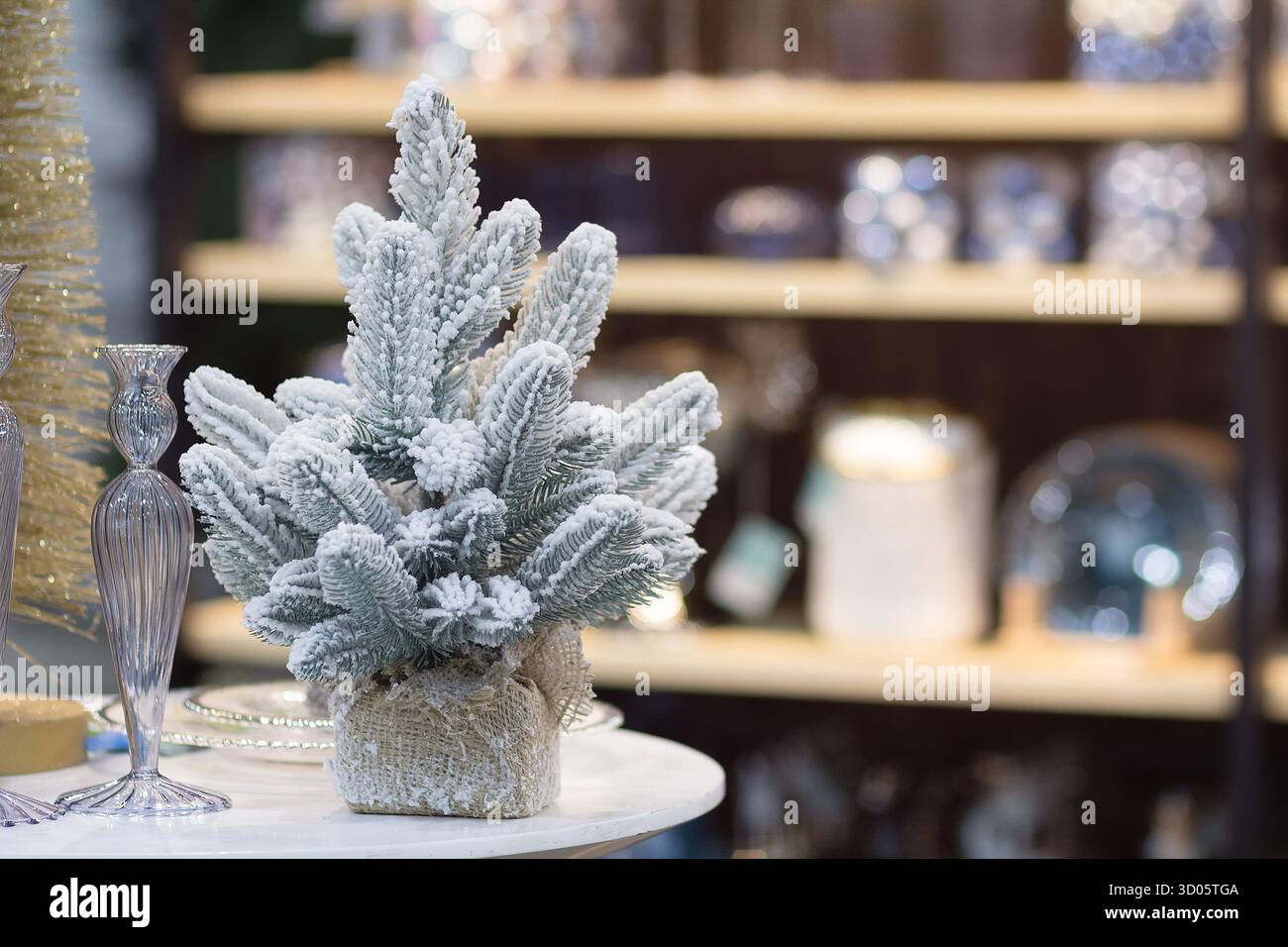 Wunderschöner kleiner, schneebedeckter Weihnachtsbaum in einem Souvenirladen. Weihnachtsdekoration Stockfoto