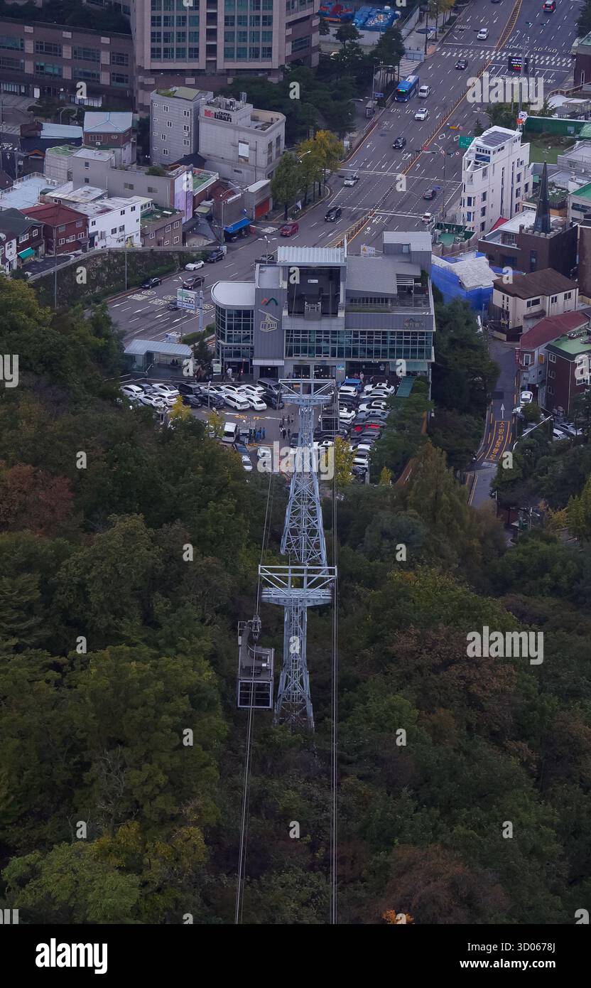 SEOUL, SÜDKOREA - 11. OKTOBER 2025 - Seilbahnkabine Namsan, die den Berg Namsan hinauffährt, mit Stadtgebäuden und Straßen darunter Stockfoto