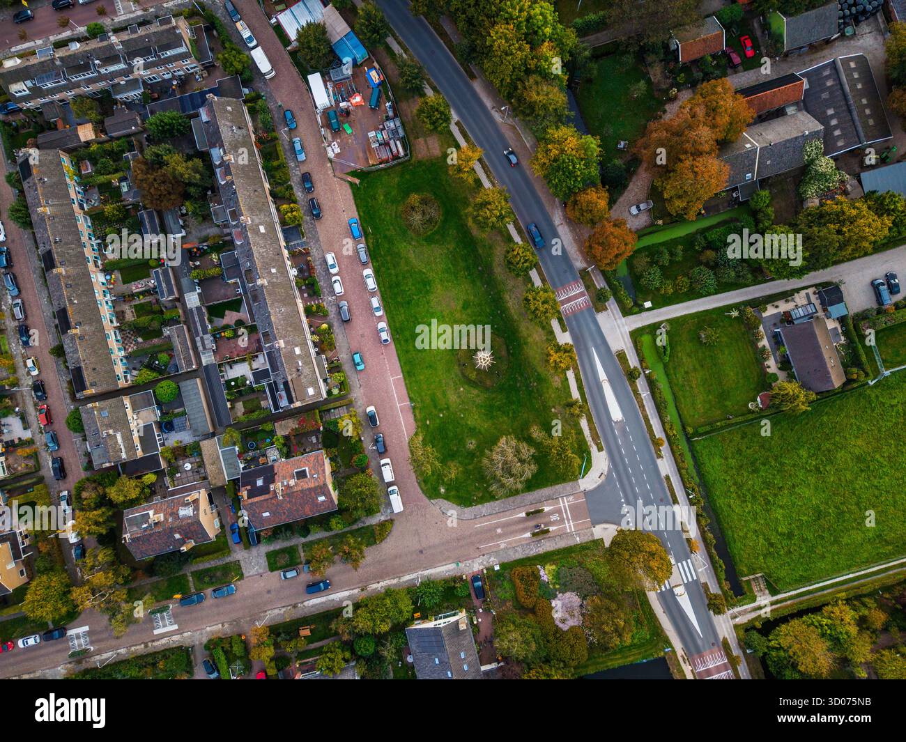 Aus der Vogelperspektive der Wohngegend Reihen von Häusern mit Gärten, zentralem grünen Park, gekrümmter Straße und offenen grasbewachsenen Feldern mit organisierter urb Stockfoto