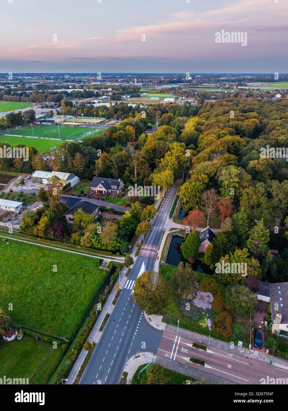 Aus der Vogelperspektive der Wohngegend Reihen von Häusern mit Gärten, zentralem grünen Park, gekrümmter Straße und offenen grasbewachsenen Feldern mit organisierter urb Stockfoto