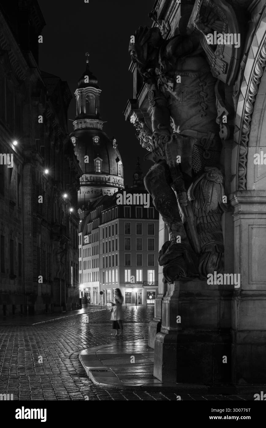 Dramatische Schwarzweiß-Nachtszene historischer europäischer Architektur mit Straßenlaternen und nassen Kopfsteinpflasterreflexionen Stockfoto