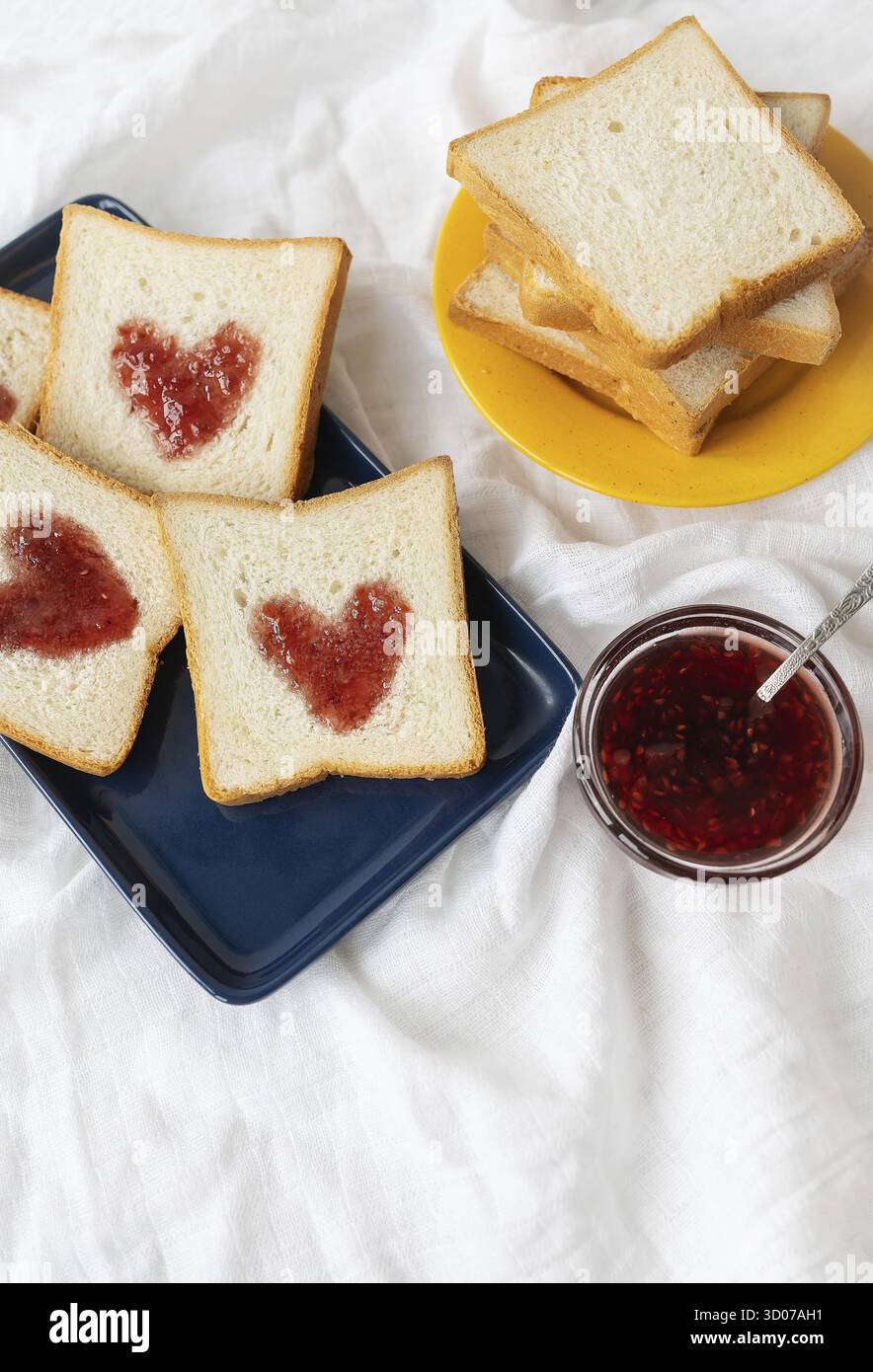 Toast, auf dem das Herz aus Marmelade besteht. Überraschungsfrühstück im Bett. Romantik zum Valentinstag Stockfoto