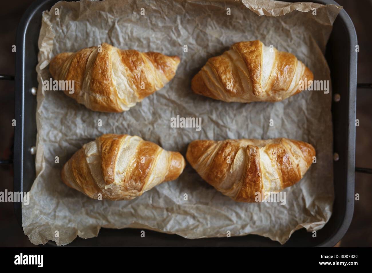 Die Croissants auf dem Tablett sind frisch aus dem Ofen, knusprig und frisch. Morgengebäck, Nachtisch für Kaffee Stockfoto