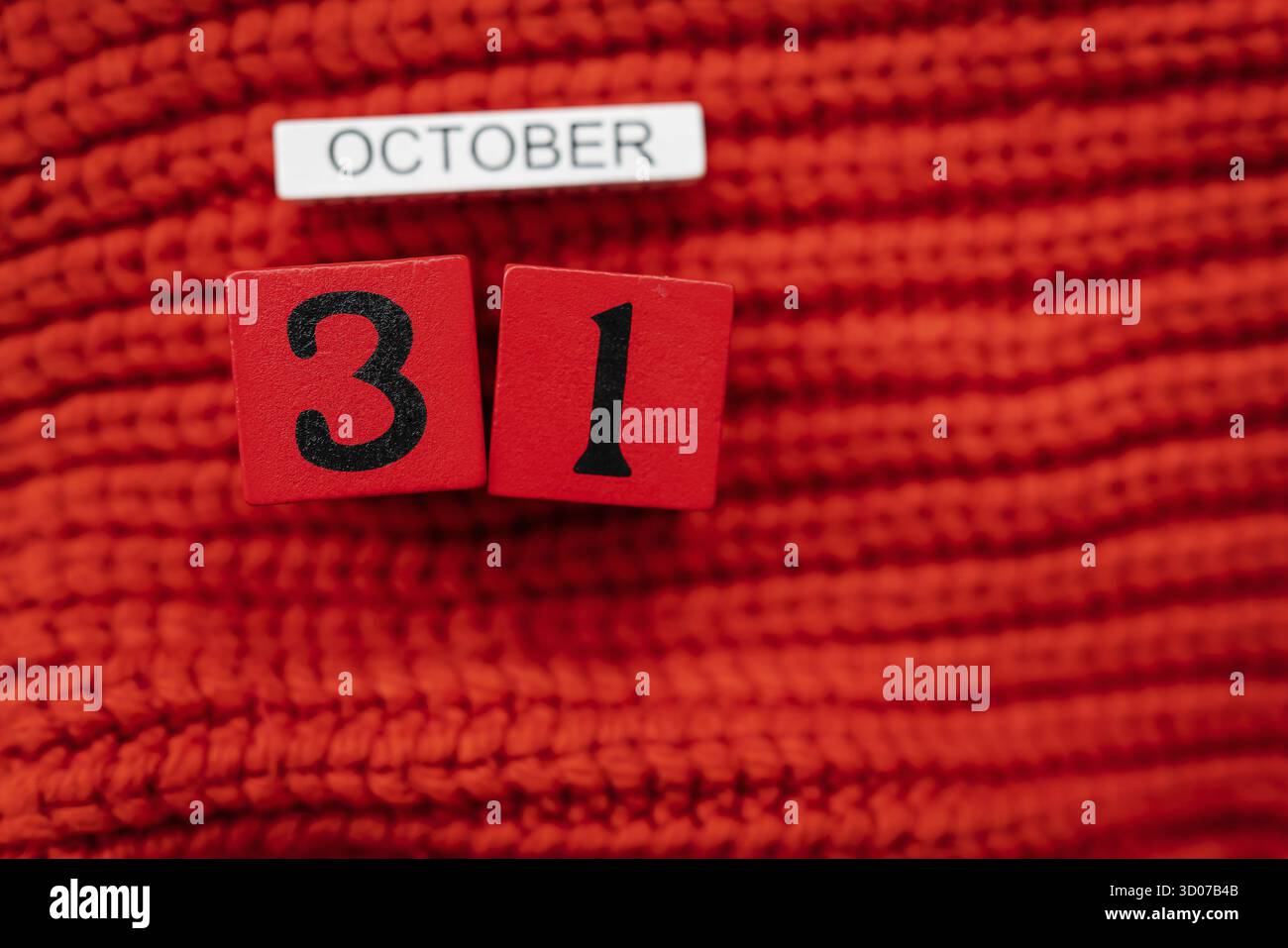 Holzwürfelkalender zeigt am 31. Oktober Halloween isoliert auf rotem Hintergrund rot gestrickter Pullover Stockfoto