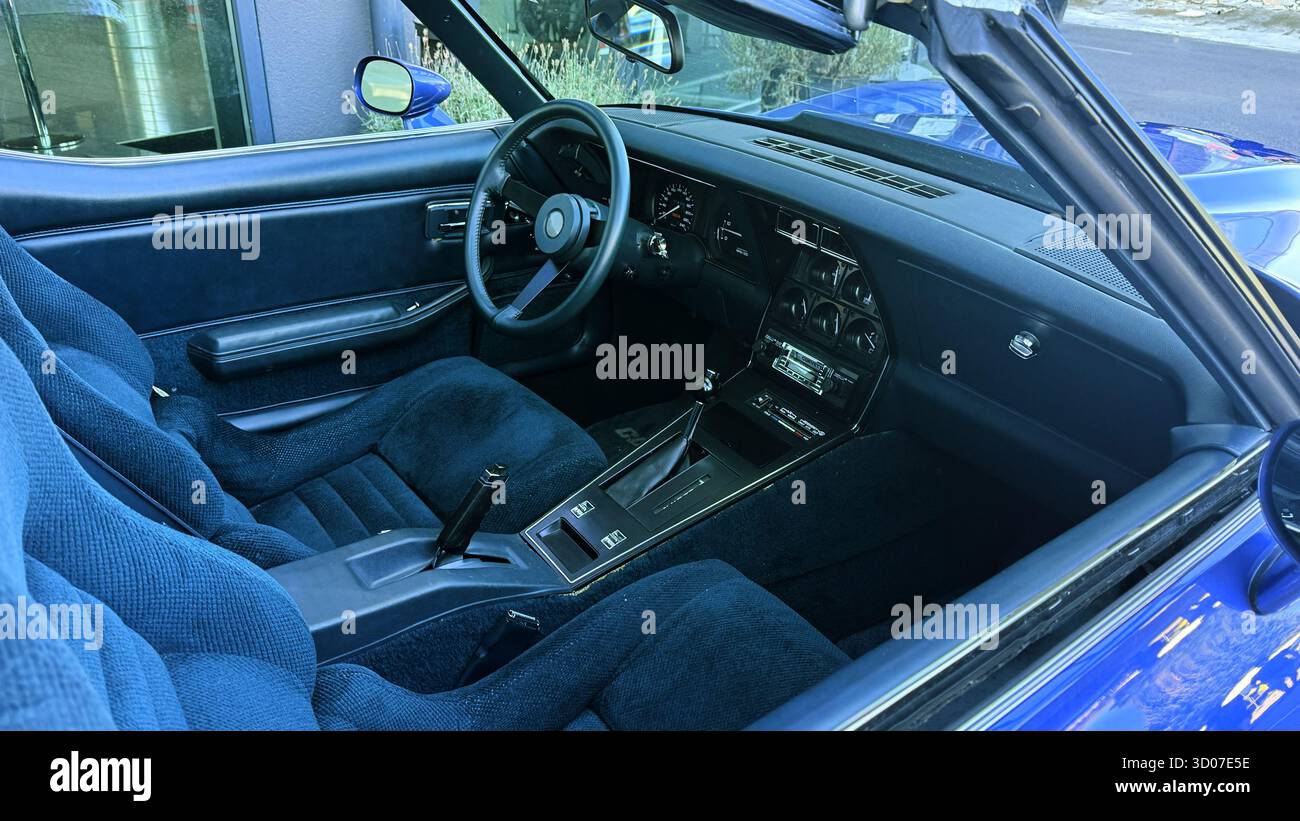 Innenraum eines klassischen blauen Sportwagens mit Vintage-Armaturenbrett und Lederlenkrad. Blick auf das Cockpit im Retro-Stil, Autorestaurierung im Innenraum - Smartphone-aufgenommenes Stockfoto