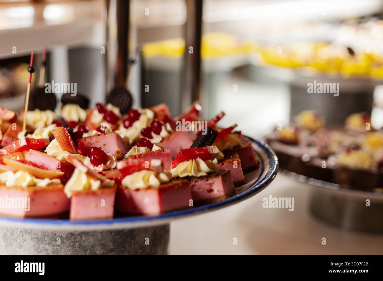 Eine köstliche Auswahl an Desserts wird an einem Tisch bei einem lebhaften Buffet serviert. Kuchen, Cremes und bunte Toppings sorgen für ein einladendes und festliches Ambiente Stockfoto
