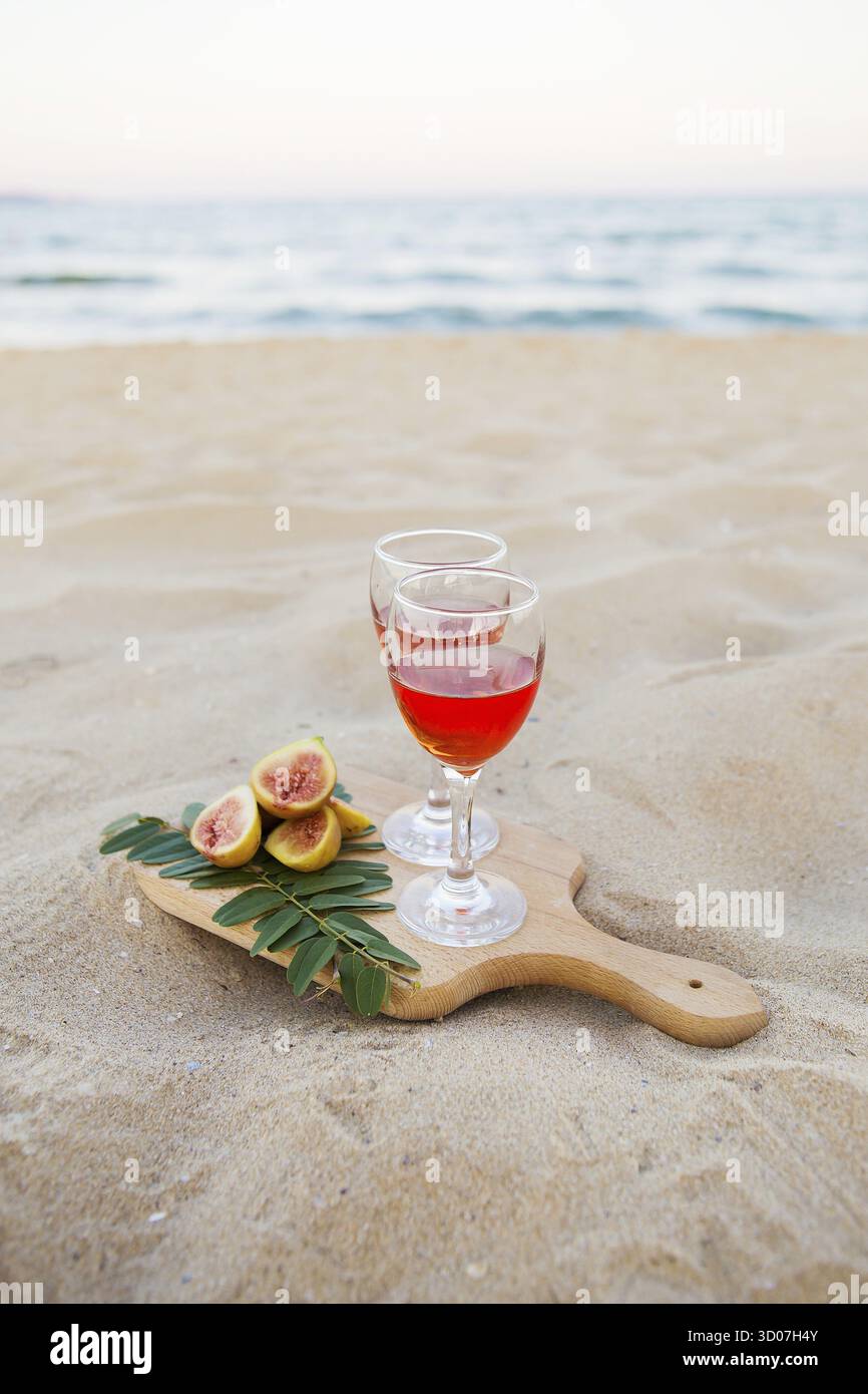 Weißes cape, Brille auf Holzbrett und Sand. Sommer-Picknick aus nächster Nähe Stockfoto