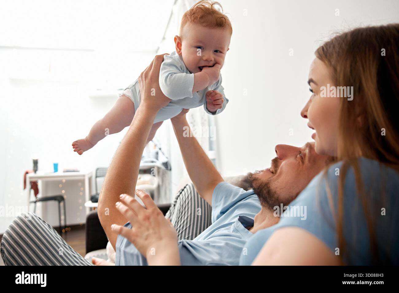 Fröhliche Familienmomente mit einem Baby, das zu Hause spielt, Eltern gemeinsam gute Zeit verbringen, ihre Bindung pflegen und das Glück feiern Stockfoto