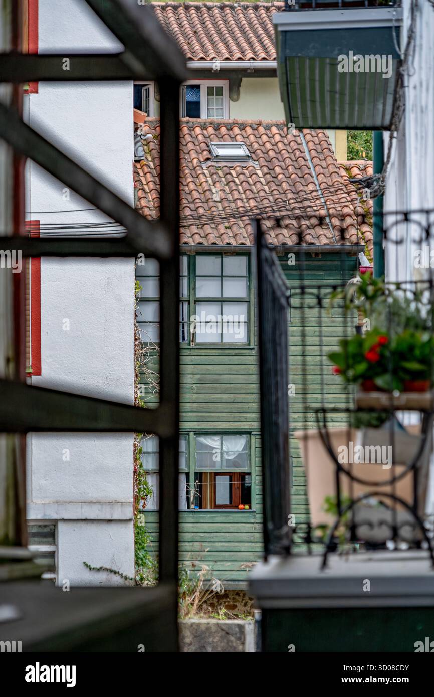 Architektonische Schichten, eingerahmt durch Balkongeländer, farbenfrohe traditionelle Holzhäuser mit Terrakottadächern, EA Village, Baskenland, Spanien Stockfoto