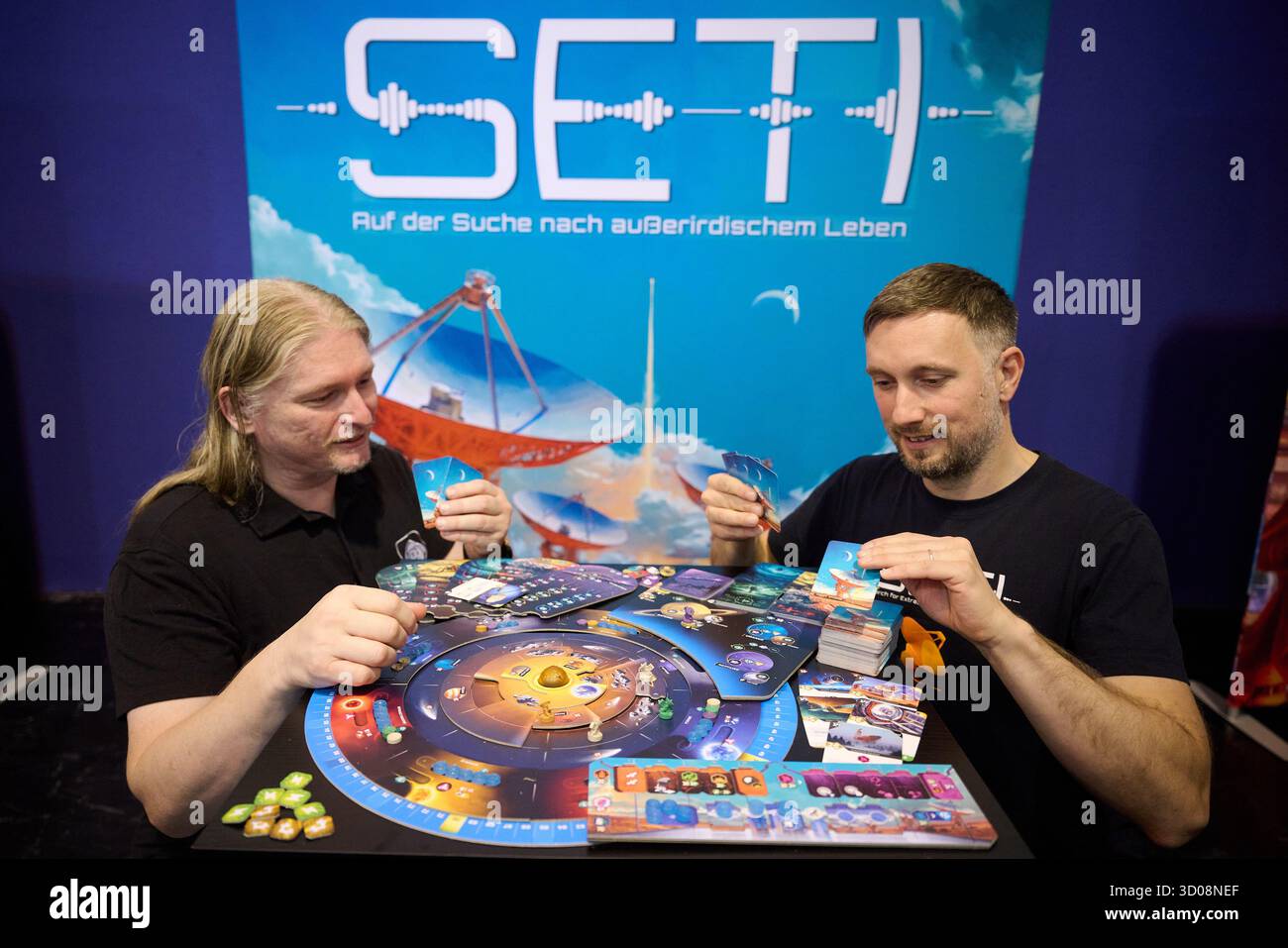 Essen, Deutschland. Oktober 2025. Petr Murmak (l) und Spieleentwickler Tomas Holek demonstrieren ihr Spiel „SETI: Auf der Suche nach außerirdischem Leben“, das zuvor mit dem Deutschen Spiele-Preis ausgezeichnet wurde, während der Medientour der internationalen Verbrauchermesse „Spiel Essen 2025“ auf der Messe Essen. Nach Angaben der Veranstalter werden ab 23. Oktober rund 200.000 Besucher aus mehr als 80 Ländern an der weltweit größten öffentlichen Brettspielmesse teilnehmen. Quelle: Bernd Thissen/dpa/Alamy Live News Stockfoto