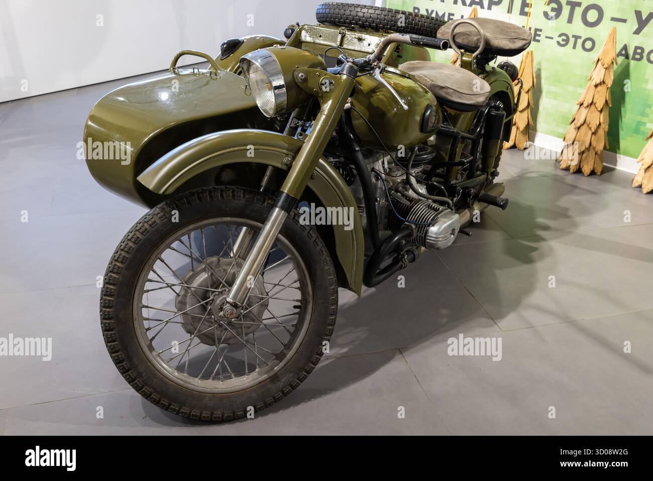 Moskau, Russland - 1. Dezember 2024: Militärisches grünes Oldtimer-Motorrad IMZ Ural M-72 mit passendem Beiwagen in einem modernen Showroom. Classic de Stockfoto