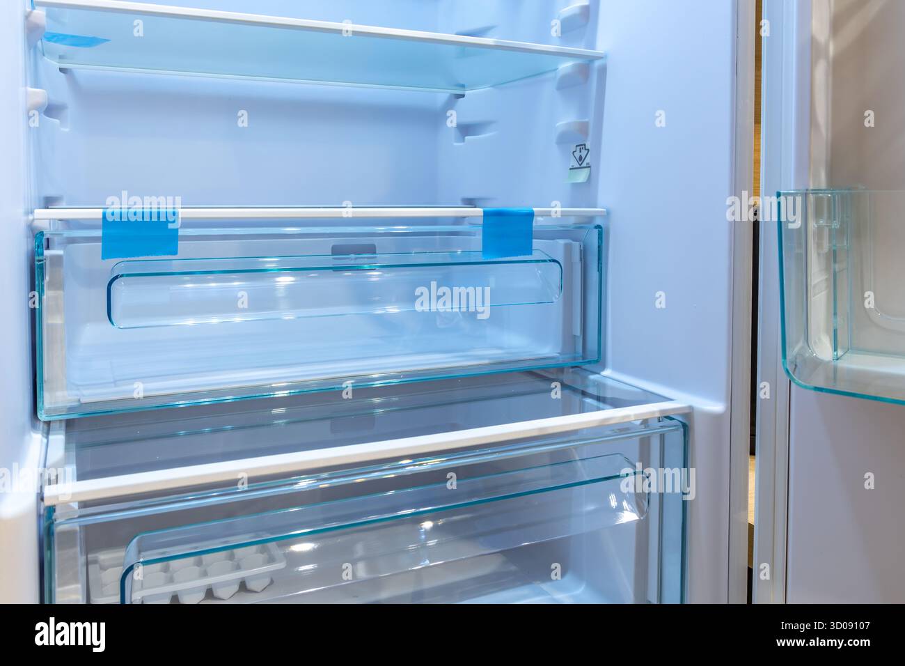 Öffnen Sie den leeren Kühlschrank mit blauer LED-Leuchte und Glasböden. Sauberes und modernes Haushaltsgeräteinnere, bereit für die Aufbewahrung von Lebensmitteln in einem modernen Stockfoto