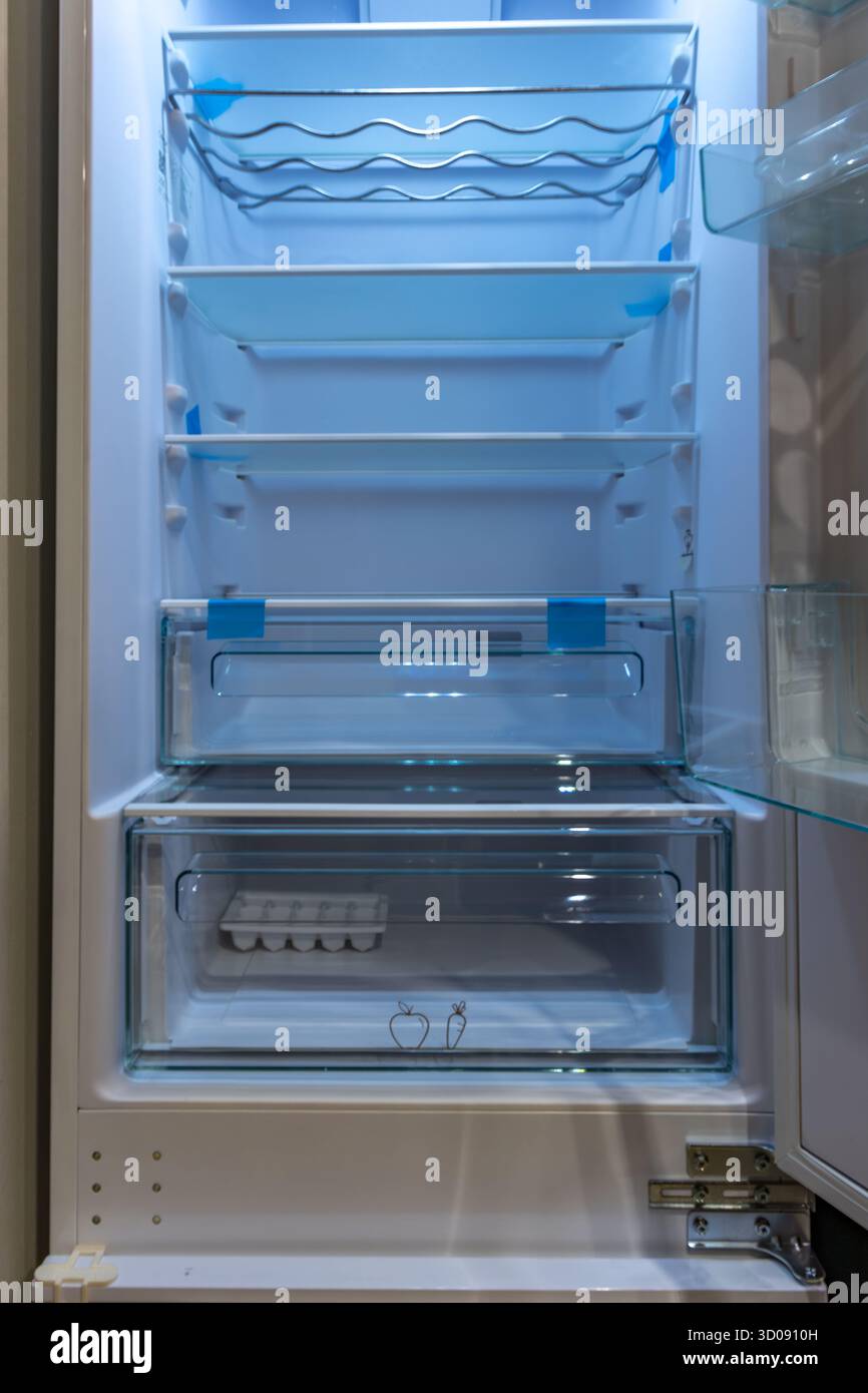 Öffnen Sie den leeren Kühlschrank mit blauer LED-Leuchte und Glasböden. Sauberes und modernes Haushaltsgeräteinnere, bereit für die Aufbewahrung von Lebensmitteln in einem modernen Stockfoto