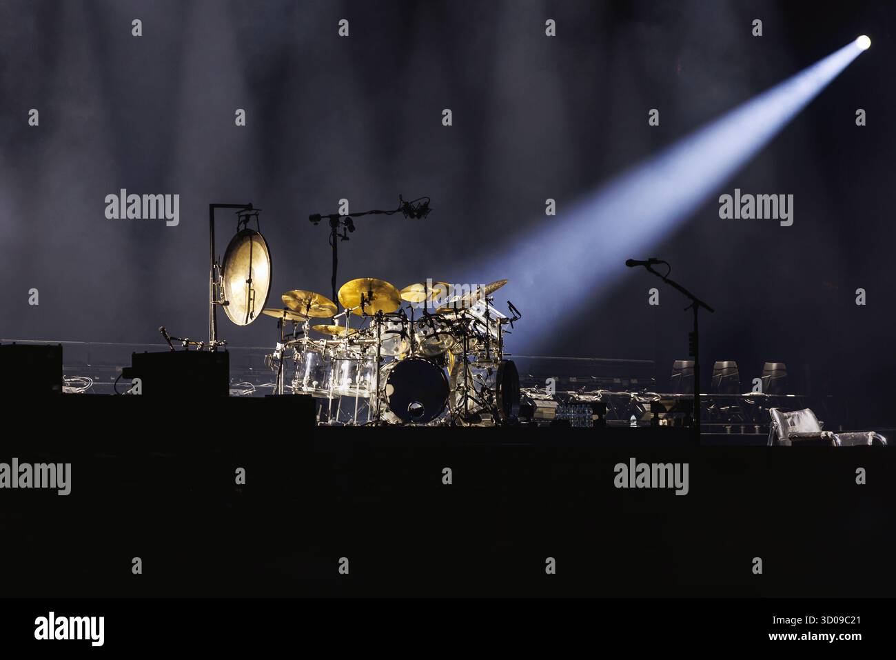 Ein detailreiches Schlagzeug, das vor Beginn der Aufführung von einem einzigen hellen Scheinwerfer auf einer dunklen Konzertbühne beleuchtet wird. Stockfoto