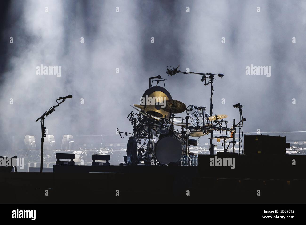 Ein komplexes Schlagzeug steht auf einer rauchgefüllten Bühne bereit, die von Scheinwerfern beleuchtet wird und wartet auf den Start der Show. Stockfoto