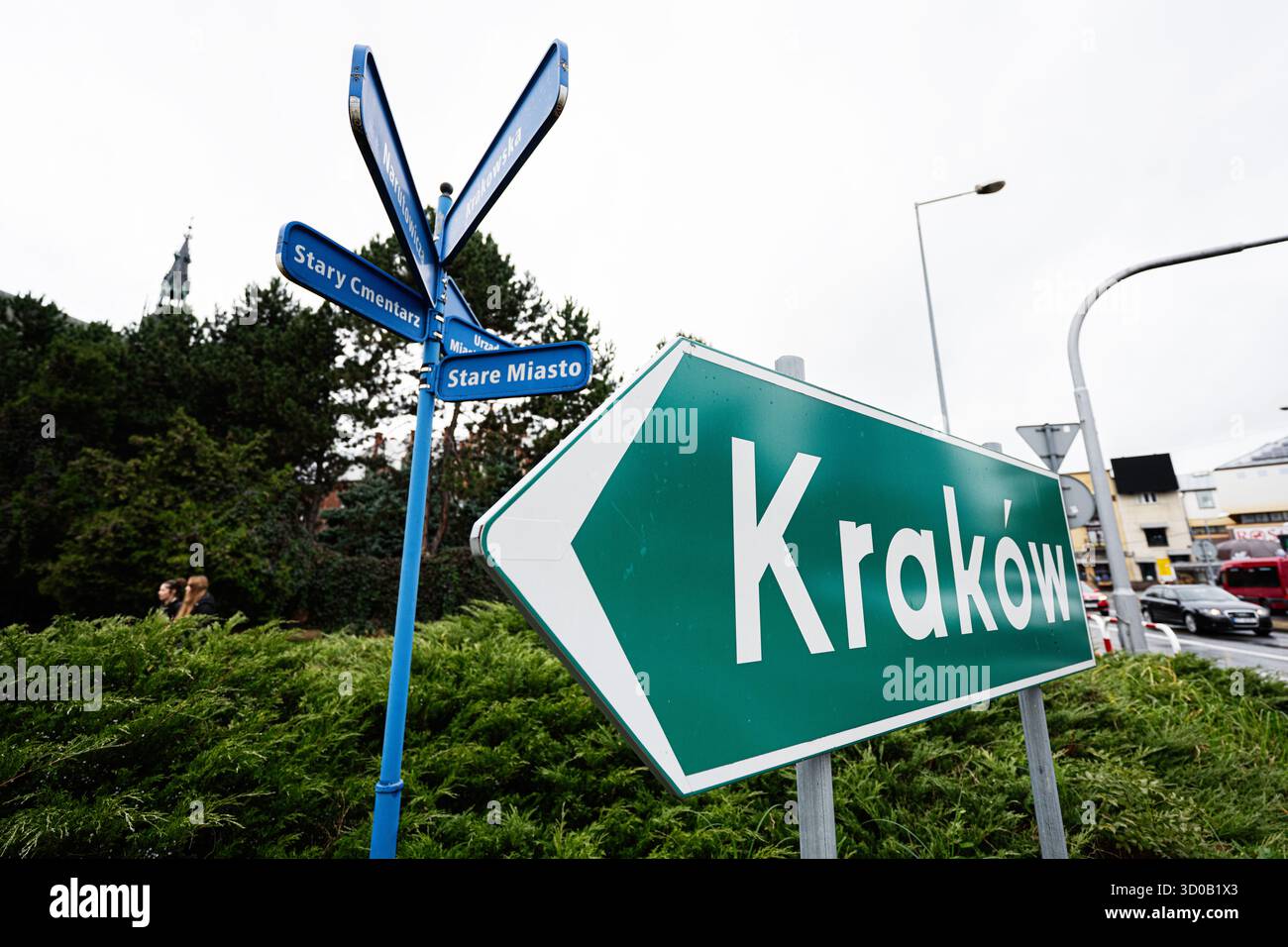 Tarnow, Polen - 10. Oktober 2025: Blauer Wegweiser in Richtung Krakau inmitten grüner und städtischer Umgebung in Tarnow, Polen. Stockfoto