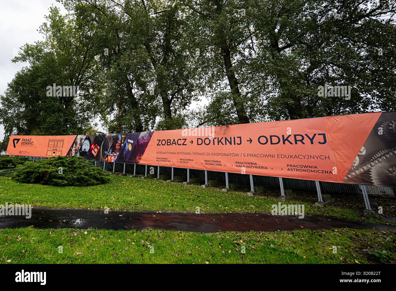 Tarnow, Polen - 10. Oktober 2025: Großes orangePasaż Odkryć-Banner zeigt interaktive Ausstellungen entlang eines Zauns in Tarnow Polen. Stockfoto