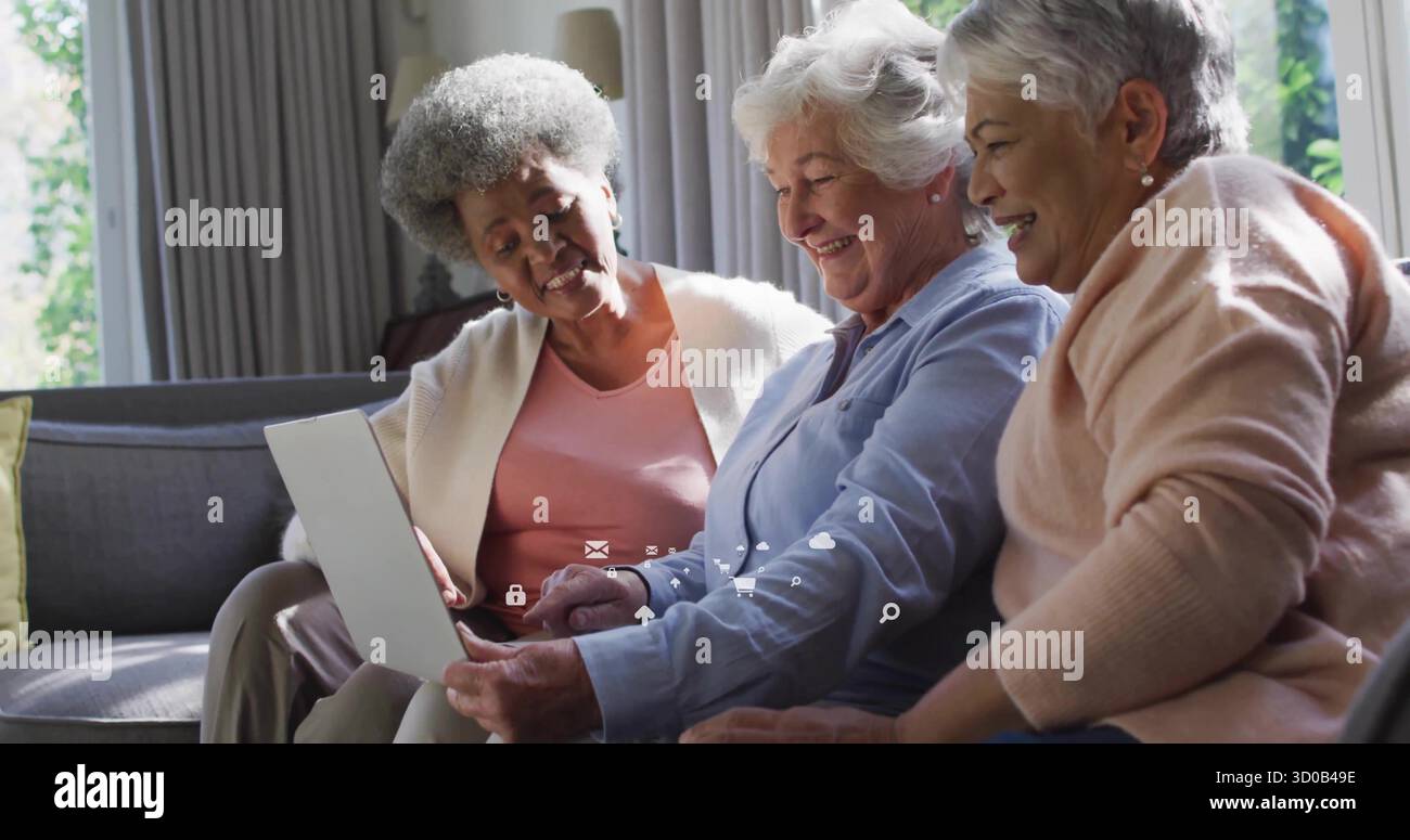 Drei ältere Frauen, die ihren Laptop auf einem Sofa im Wohnzimmer erkunden, mit hellen Vorhängen und Tischlampe Stockfoto