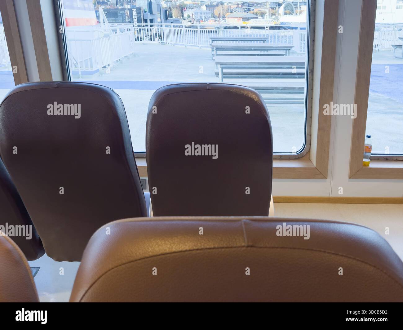 Komfortable braune Ledersitze in der Fähre von Tirghattan mit Blick auf ein großes Fenster mit Blick auf den Sitzbereich im Freien, einladend Stockfoto
