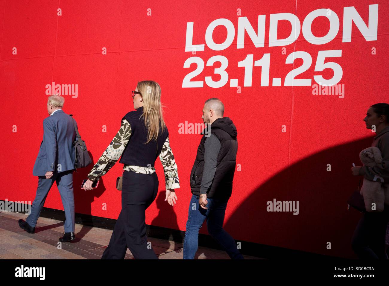 Am 22. Oktober 2025 im Oxford Circus in London, England, laufen die Käufer unter einer Werbetafel für die Nike Sportmarke. Das Datum des 23. November 2025 bezieht sich auf ein Event, das Nike an diesem Tag auf der Excel ausrichtet, bei dem Sportlerinnen mit einer 1K-Qualifikation konfrontiert werden, die festlegt, in welchem von drei 10K-Rennen sie antreten können, sowie auf einer geeigneten Strecke, die für Geschwindigkeit und Ausdauer ausgelegt ist. Stockfoto