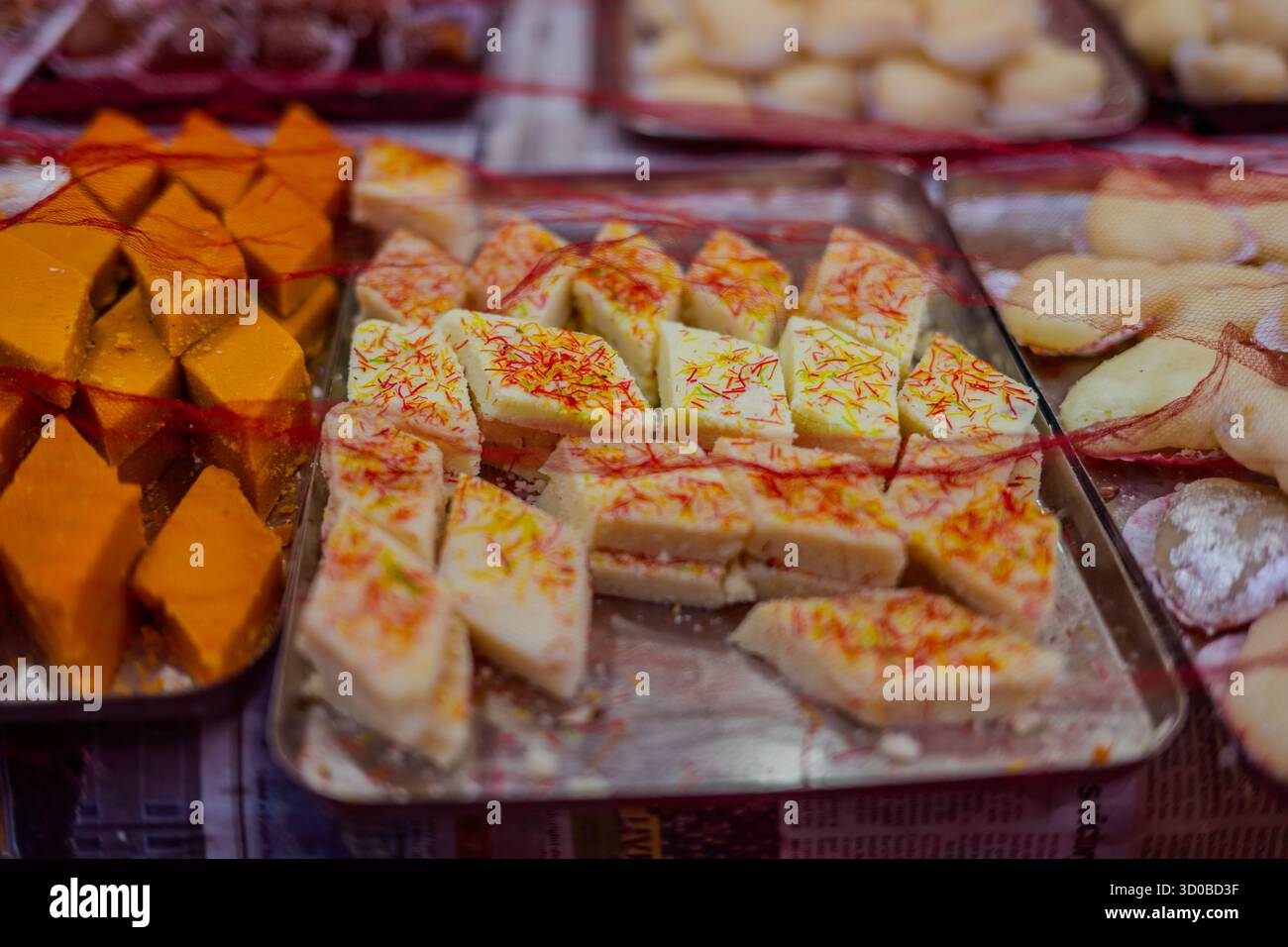 Auswahl traditioneller nepalesischer Süßigkeiten auf Tabletts in einem lokalen Geschäft in Kathmandu, Nepal – 20. Oktober 2025. Stockfoto