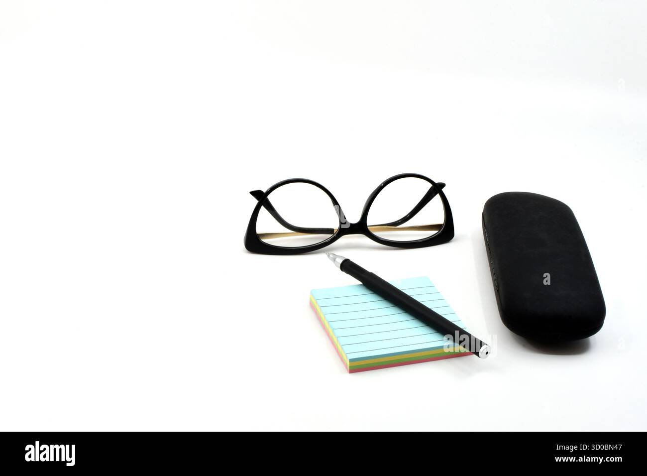 Stift auf einem Block mit Erinnerungsnotizen mit einer Damenbrille und einem Brillenetui auf weißem Hintergrund. Kopierbereich. Keine Personen. Stockfoto