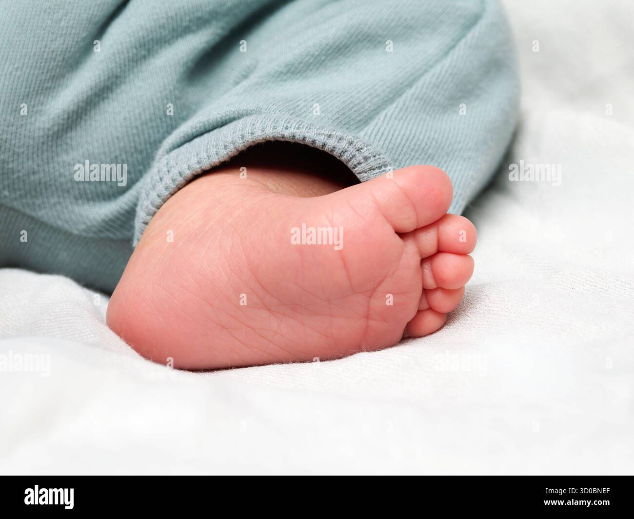Nahaufnahme eines Babyfußes im grauen Pyjama, friedliches Symbol der kindlichen Zärtlichkeit. Stockfoto