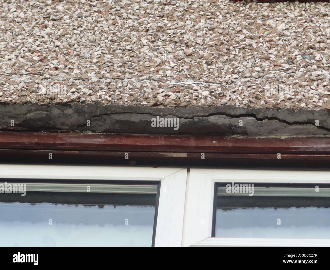 Wohnungsreparaturen: Risse im Mörtel über einem Fenster weisen auf einen Verfall hin und dass ein struktureller Sturz ersetzt werden muss. Stockfoto