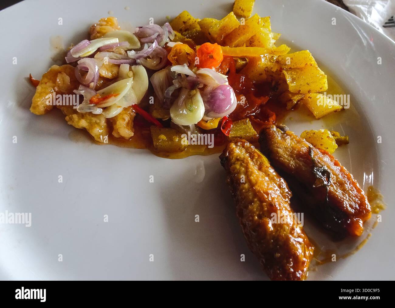 Teller mit verschiedenen Buffetprodukten, darunter Hähnchenflügel, Kartoffeln und Knoblauch, mit einer Vielzahl frisch zubereiteter herzhafter Speisen. Stockfoto