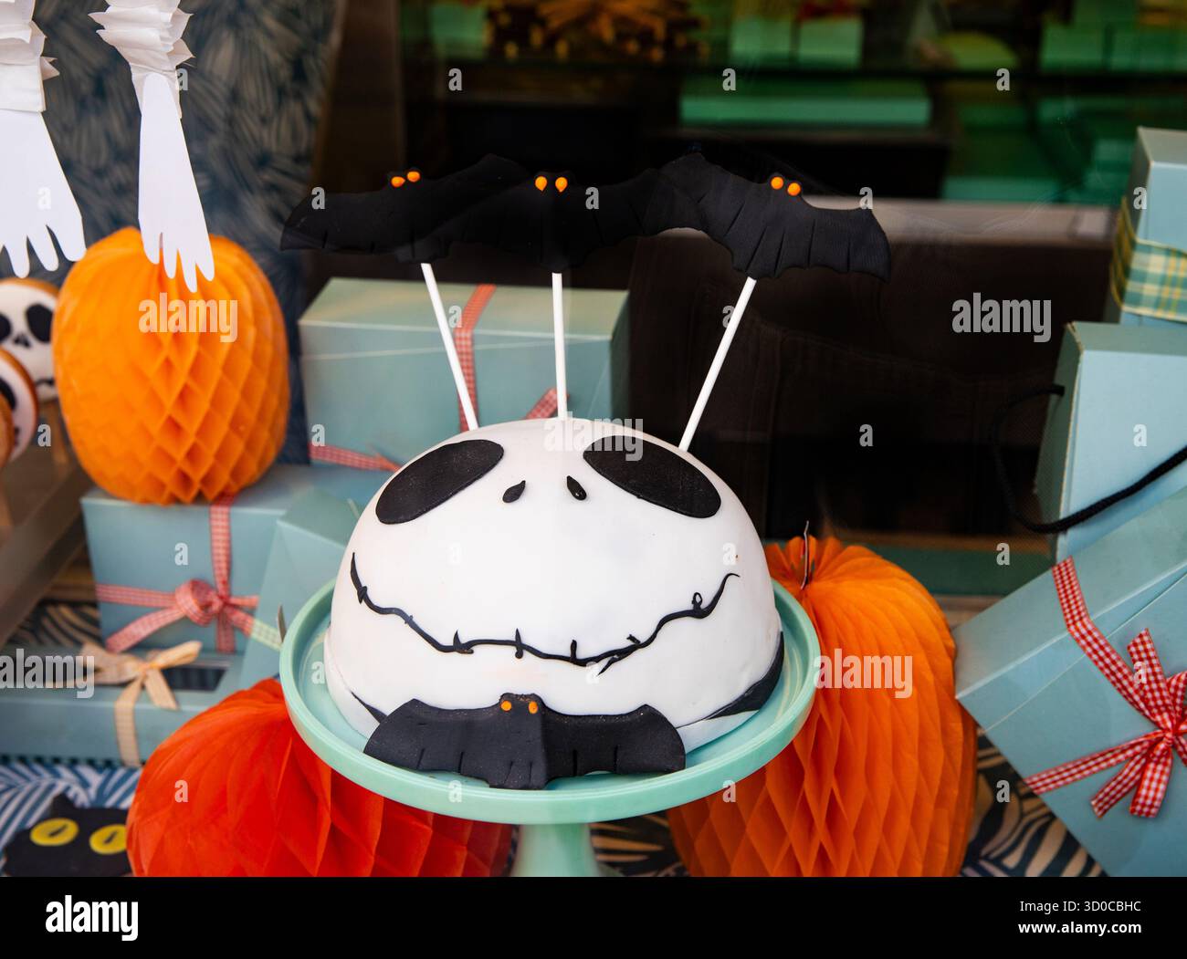 Desserttisch für Feiertage mit Süßigkeiten und blauen und orangen Schachteln. Jack Skellington Fledermauskuchen für Halloween-Dekoration Stockfoto