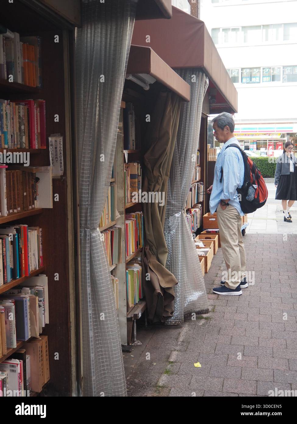 Mann, der in einem Buchladen im Freien in Jimbocho, Tokio, Japan, gebrauchte Bücher durchsucht Stockfoto