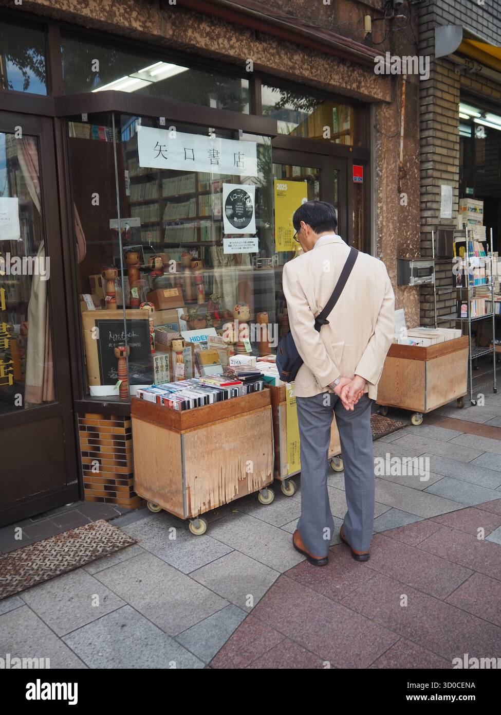 Mann, der in einem Buchladen im Freien in Jimbocho, Tokio, Japan, gebrauchte Bücher durchsucht Stockfoto