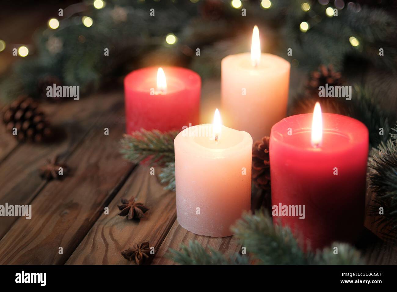 Kerzen auf rustikalem Holz. Ruhige Weihnachtsstimmung mit brennenden Adventskerzen und Tannenzweigen in dunklem Ambiente Stockfoto