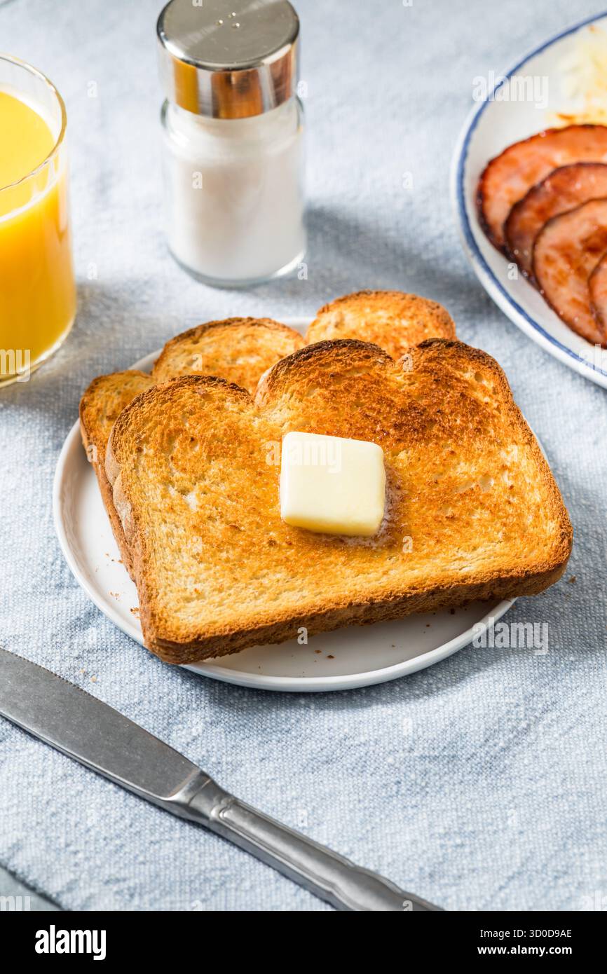 Hausgemachter Toast mit Butter zum Frühstück mit Orangensaft Stockfoto