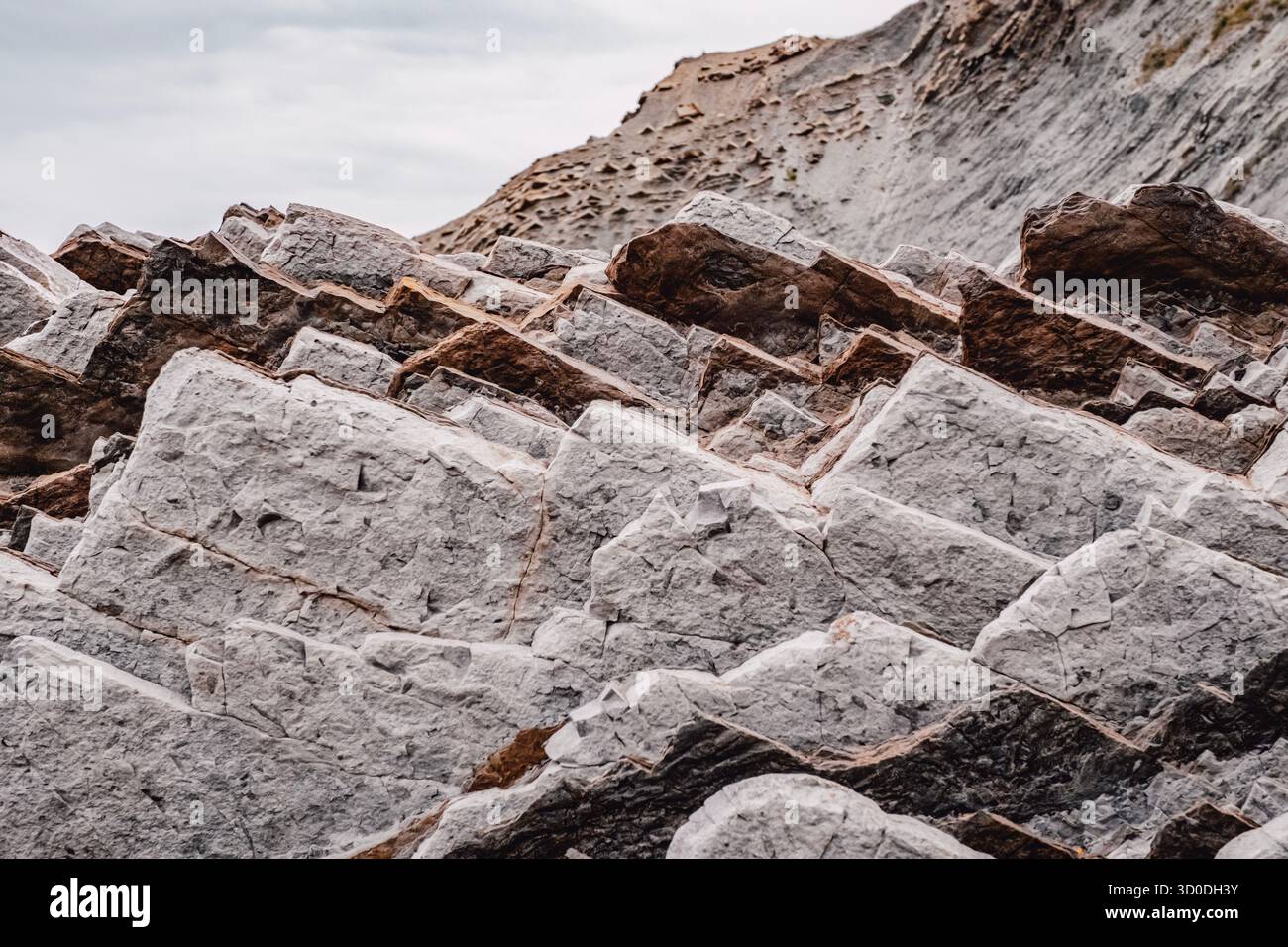 Geschichtete Sedimentgesteinsformation mit geologischen Schichten, natürlichen Erosionsmustern, weißen und braunen Steinschichten, strukturierten Oberflächendetails Stockfoto