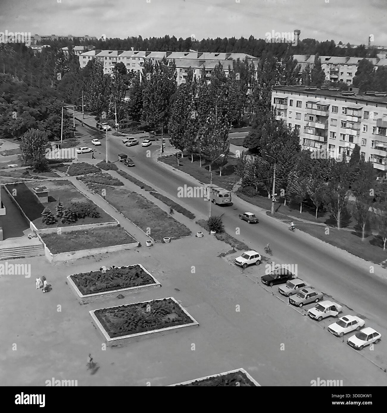 Ein Blick aus der Vogelperspektive auf den Platz vor der Pädagogischen Universität in Sloviansk, Ukraine, 1997. Das Foto zeigt die General Batyuk Street und den Artyoma Microdistrikt. Auf der Straße gibt es Verkehr und geparkte Autos (VAZ-Modelle). Man läuft auf dem universitätsplatz mit seinen großen Blumenbeeten. Im Hintergrund befinden sich typische Tafelwohnungen aus der sowjetischen Zeit („Panelka“). Dies ist ein nostalgischer Blick auf eine postsowjetische Stadt in den 1990er Jahren Ein wertvolles Dokument über das friedliche Leben im Donbass vor dem Krieg Stockfoto
