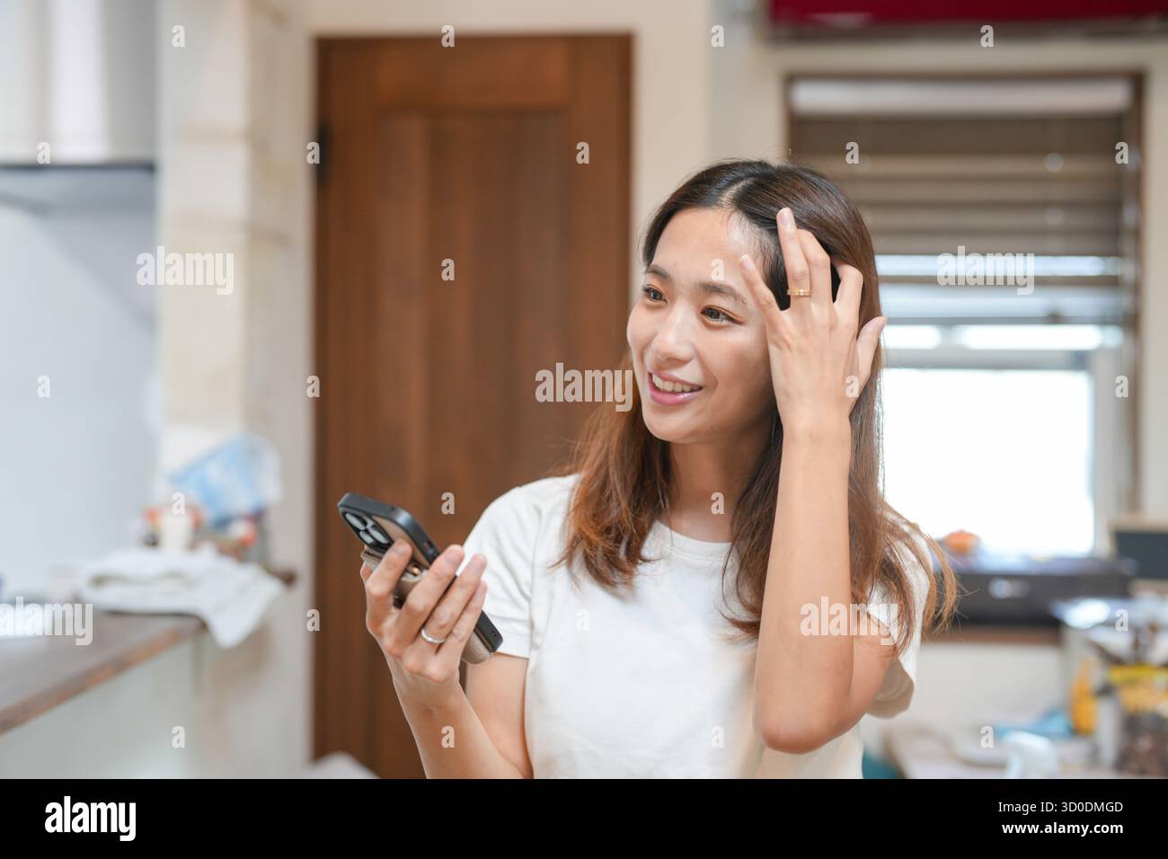 Eine Frau schaut auf ihr Handy, während sie sich vorbereitet. Sie lächelt und ist gut gelaunt Stockfoto