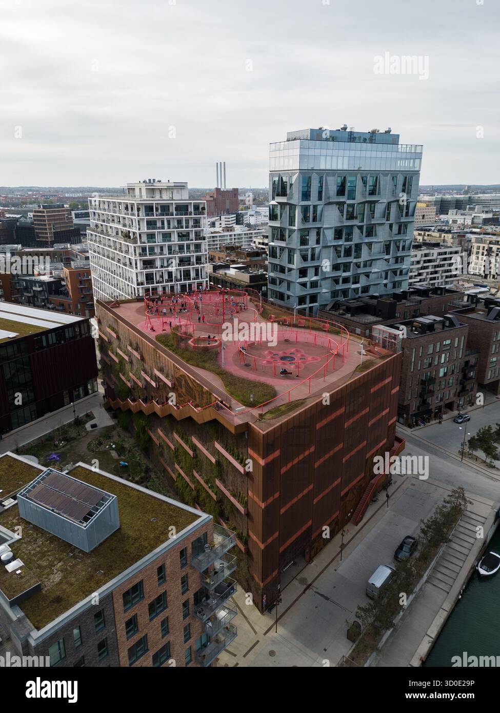 Blick aus der Vogelperspektive auf moderne Architektur, die Erdtöne mit lebhaftem Spielplatz auf dem Dach verbindet, Helsinki, Kopenhagen, Dänemark. Stockfoto