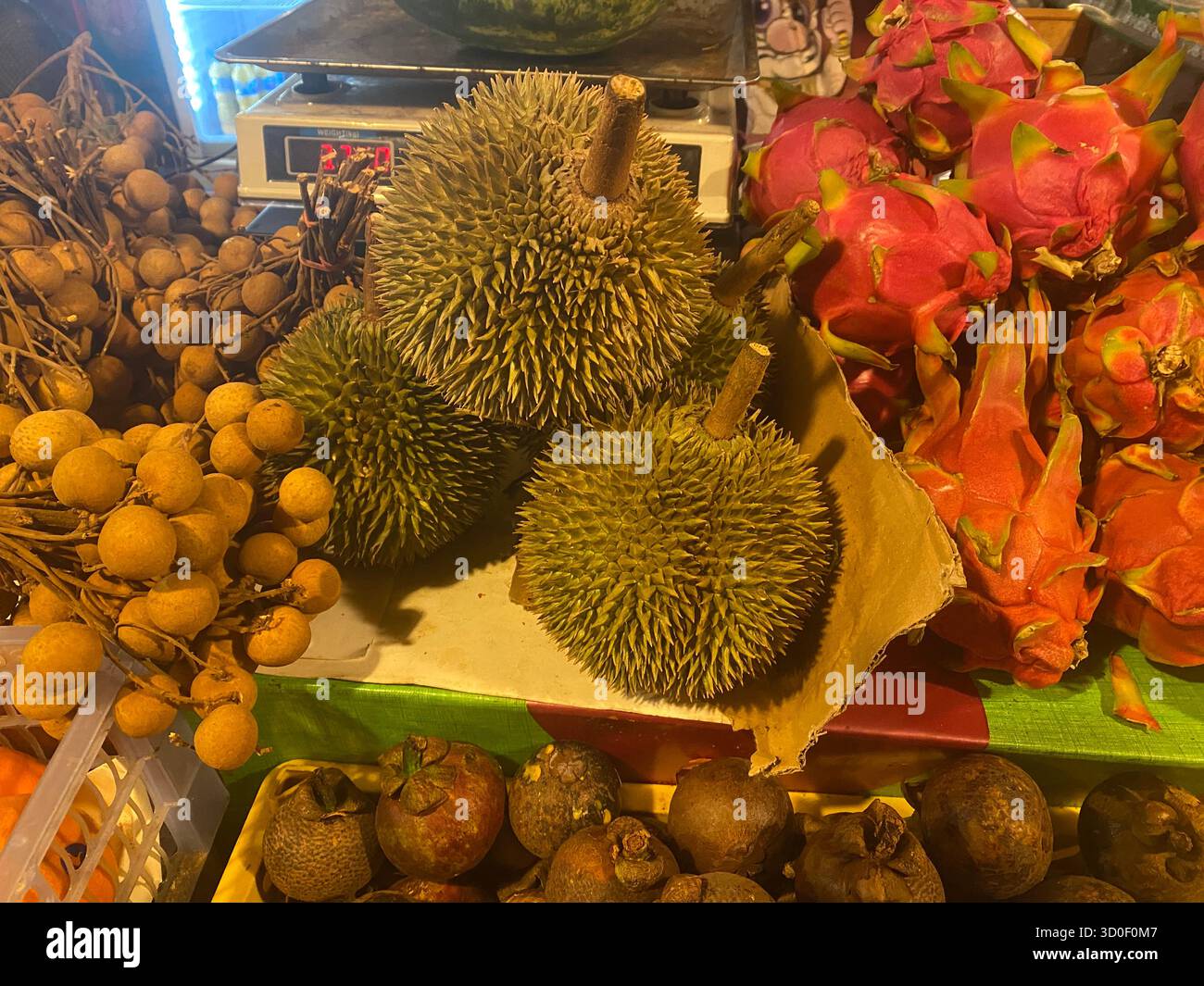 Ein thailändischer Obststand auf dem Pattaya Nachtmarkt. Durian, Drachenfrucht, Mangostan und Longan. Stockfoto