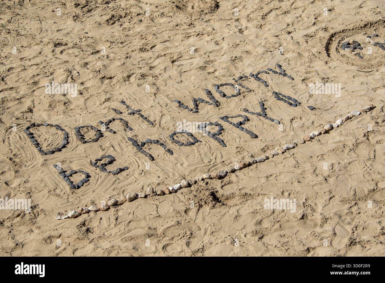 Keine Sorge, sei glücklich, mit Steinen im Sand Stockfoto