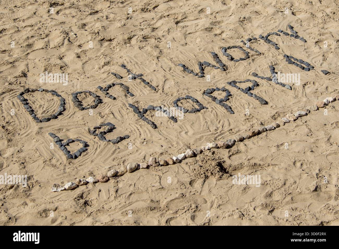 Keine Sorge, sei glücklich, mit Steinen im Sand Stockfoto