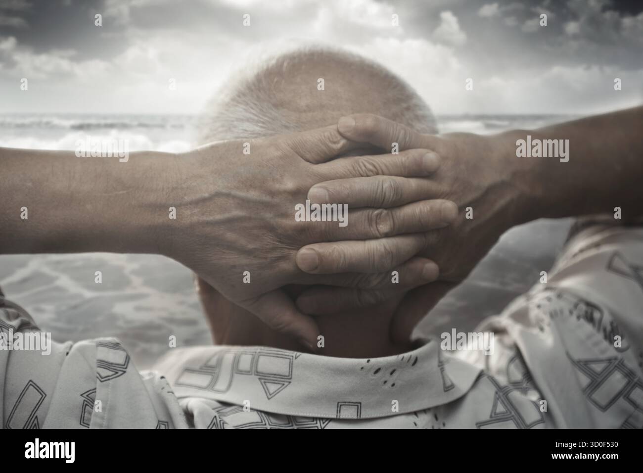 Ältere Mann mit Händen hinter dem Kopf, Blick auf das Meer Stockfoto