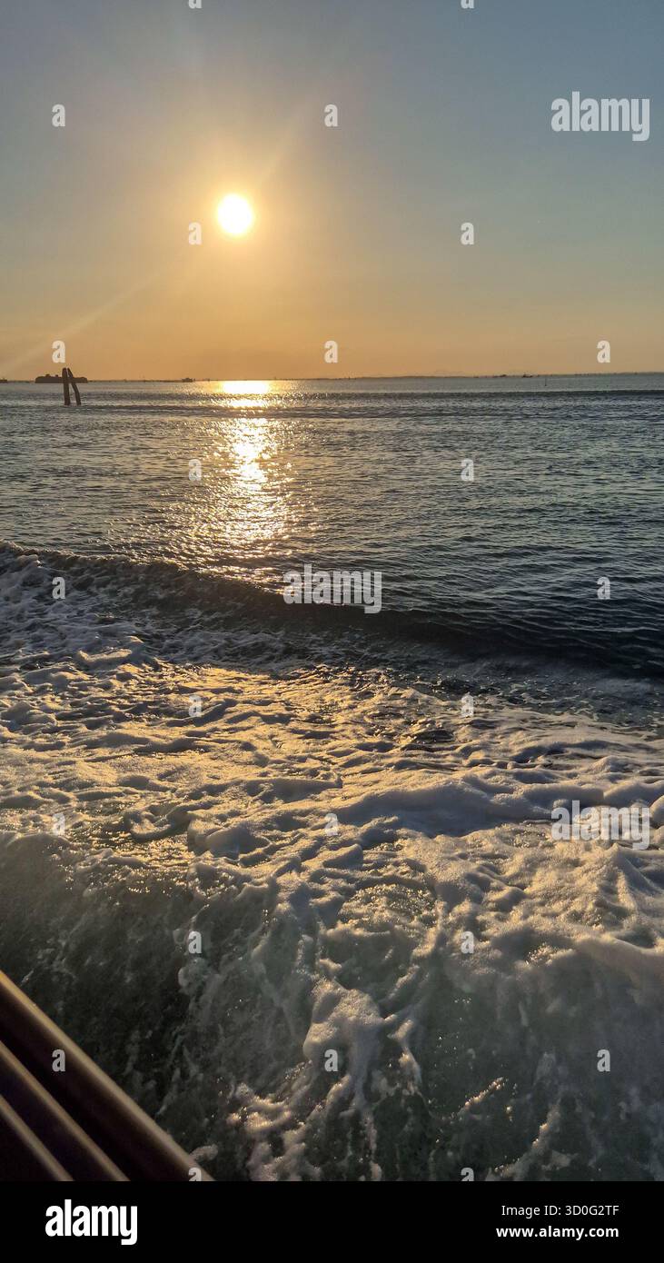 Adria Sonnenuntergangslandschaft in der Nähe von Venedig, Italien, goldenes Abendlicht über ruhigem Küstenwasser. - Smartphone-aufgenommenes Stockfoto