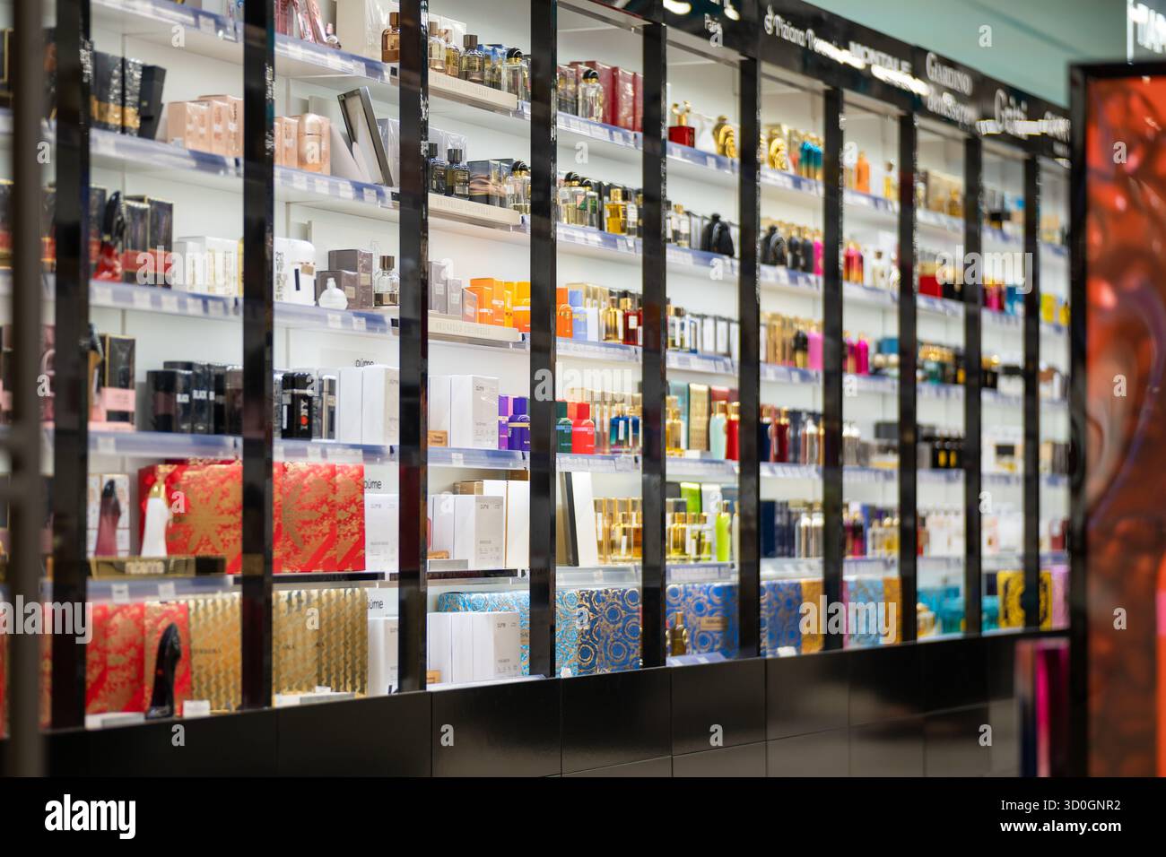 Grodno, Weißrussland - 28. August 2025: Ein gut beleuchtetes, unscharfes Hintergrundbild einer Wandvitrine, gefüllt mit einer Auswahl an Designer-Parfümflaschen und pac Stockfoto