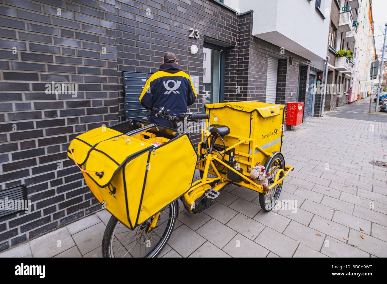 DHL Deutsche Post-Mitarbeiter, der Post mit Lastenfahrrad vor der Tür zustellt Stockfoto