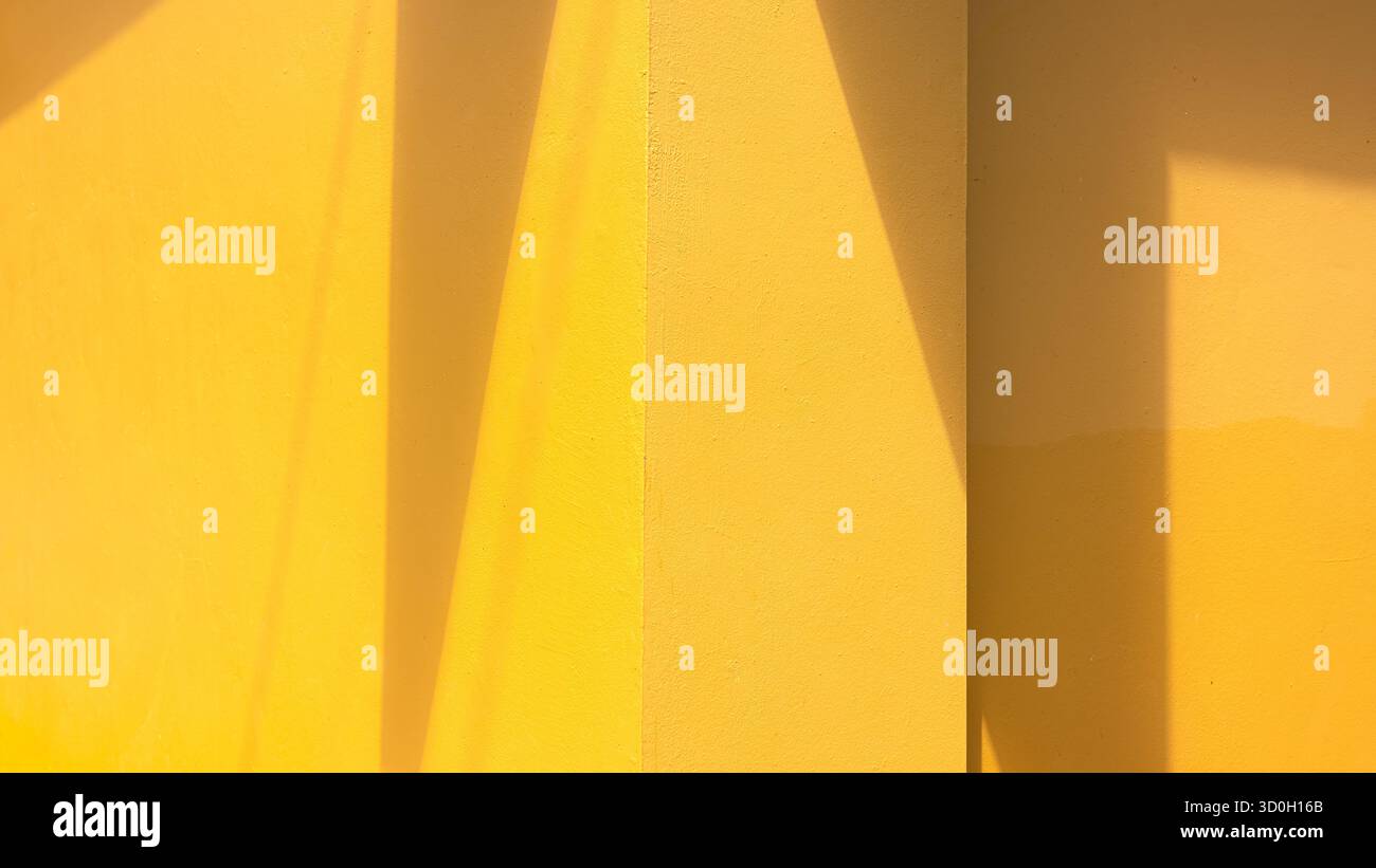 Minimale gelbe Wand mit geometrischem Sonnenlicht-Schatten. Moderner abstrakter Architekturhintergrund für Design, kreatives Layout und ästhetische Präsentation. Stockfoto