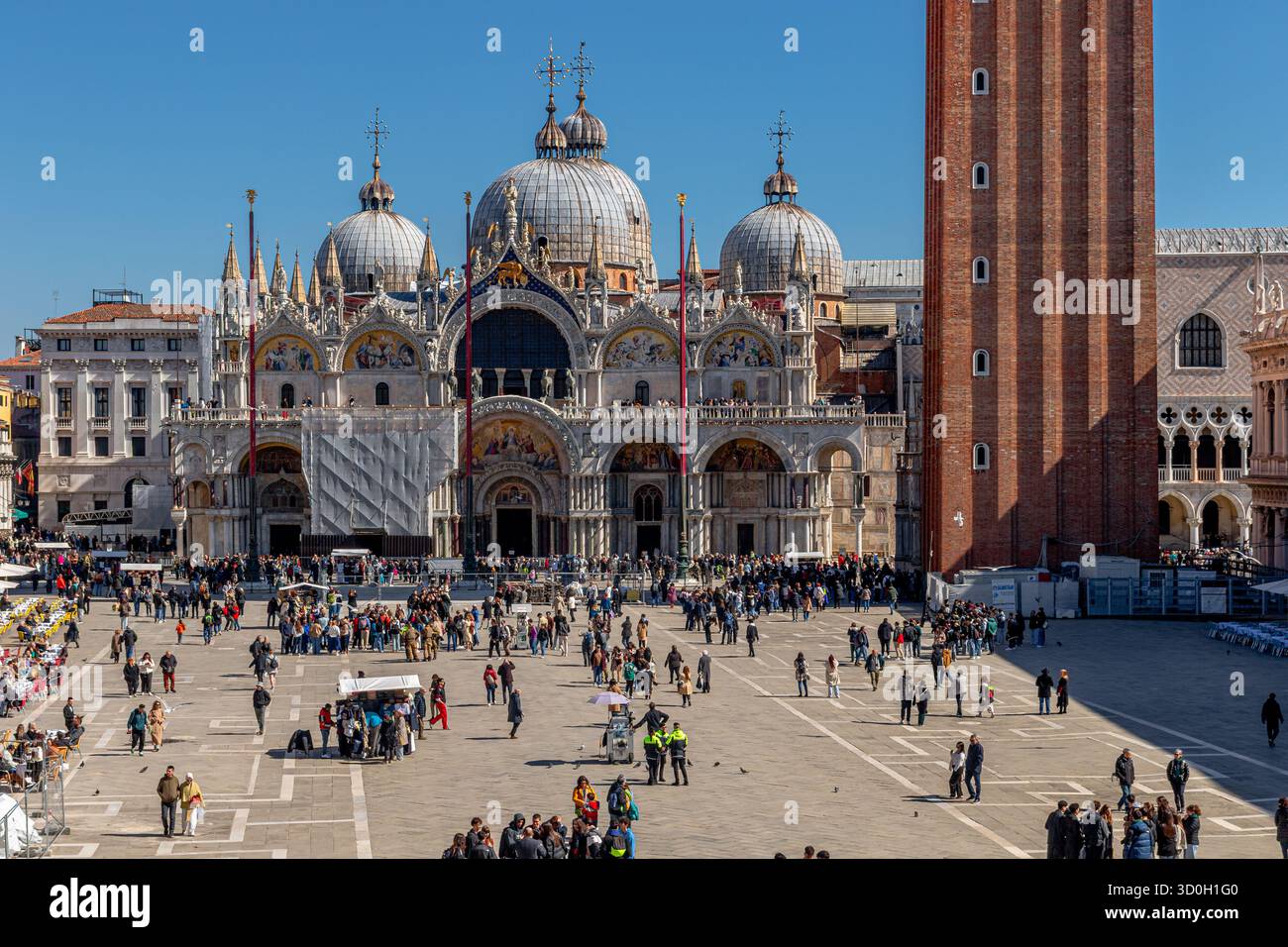 Menschenmassen auf dem Markusplatz mit den byzantinischen Kuppeln des Markusdoms am östlichen Ende des Markusplatzes in Venedig, Italien Stockfoto