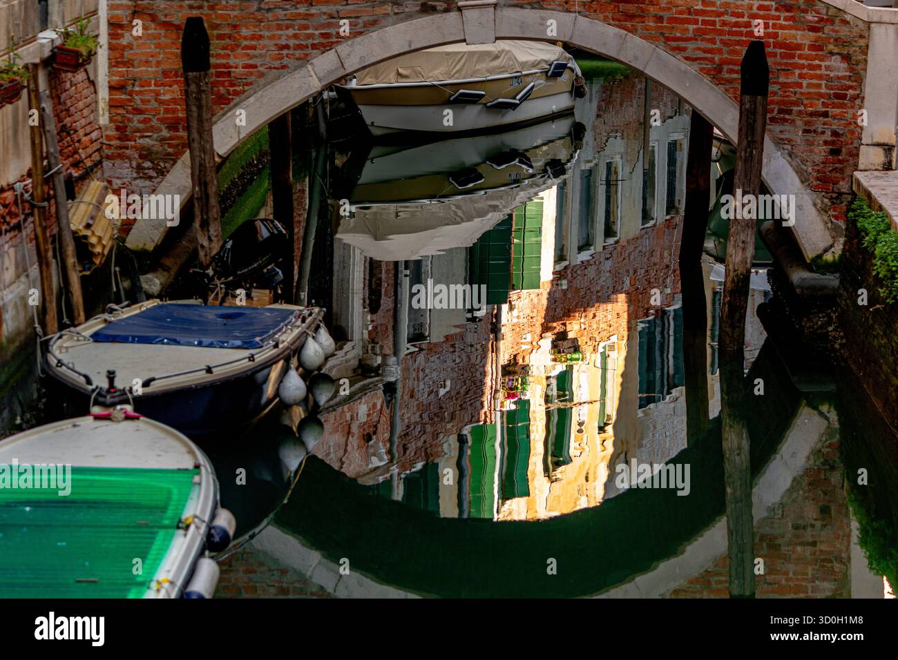 Gebäude spiegeln sich im stillen Kanalwasser von Rio de la Muneghete neben der Ponte de le Sechere, einer Kanalbrücke in Santa Croce, Venedig, Italien Stockfoto