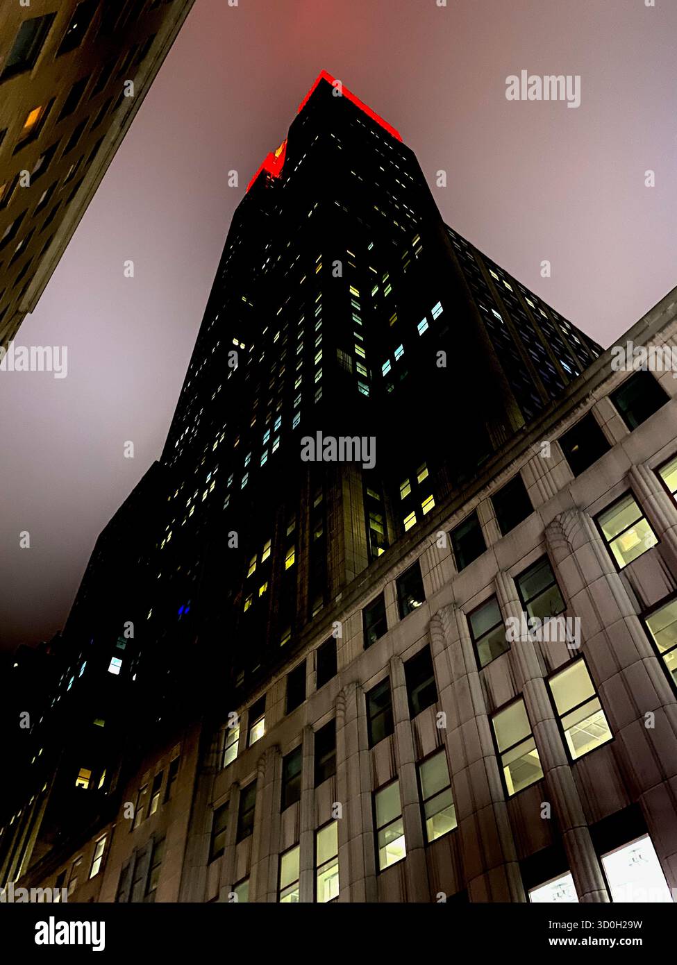 Das Empire State Building in Rot an einer kalten, nebeligen Nacht von unten. - Smartphone-aufgenommenes Stockfoto